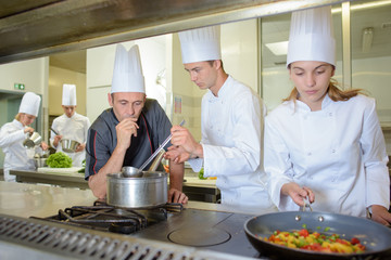 Chef supervising trainees cooking