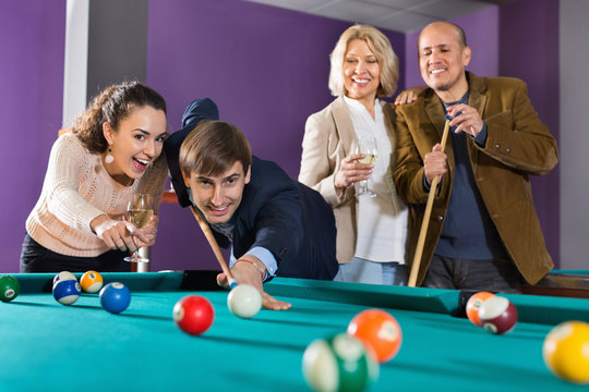 Group of  positive friends playing billiards