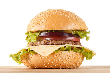 Traditional American cheeseburger. Meat, bun and vegetables close up