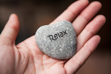 Inner balance concept: hands holding stones with the word relax