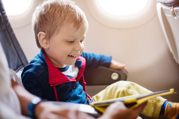 Little boy using tablet on board of aircraft 