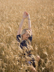 Attractive blonde walking and posing on a rye field in summer da