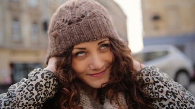 Cute young woman wearing her brown hat in the street.