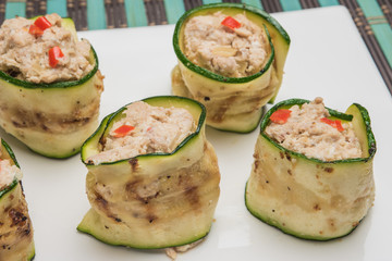 Grilled zucchini rolls with curd cheese and tuna on plate.