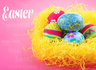 Easter greeting card. Multicoloured eggs in straw on pink background