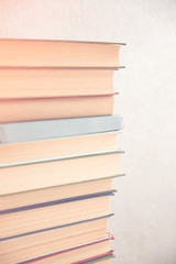 Stack of books on light wall background, close up