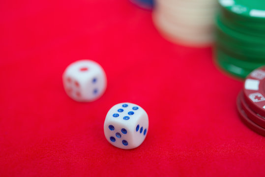 dices and poker chips on red casino table