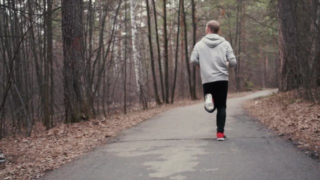 Man running in forest woods training and look at smart watches.