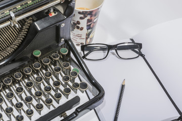 antique typewriter with coffe, a blank and a pencil on white background