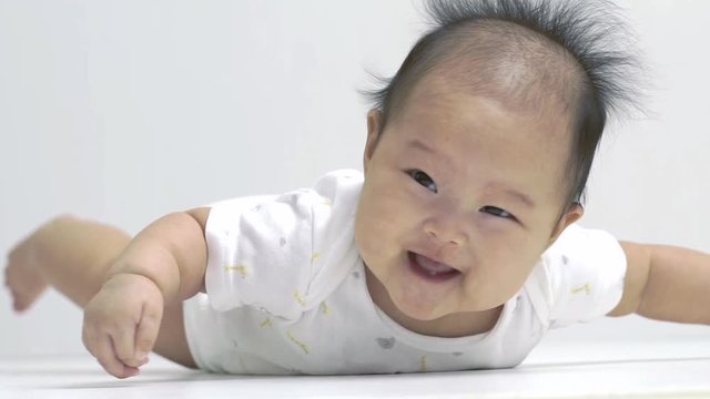 Cute little asian chinese baby on her tummy smiling