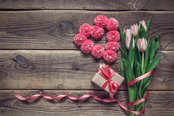 Background with a bouquet of tulips, gift box and a heart shape