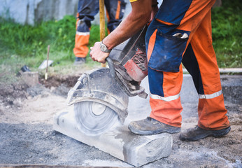 Construction worker cutting concrete paving stabs or metal for s