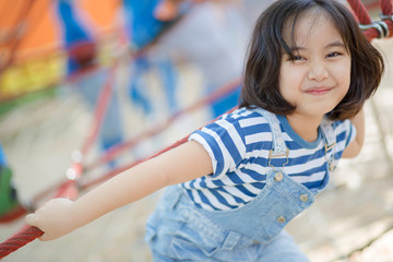 Cute children. Asian girl climbing in a rope playground structure at adventure park