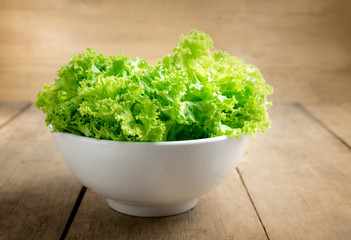 Lettuce in white bowl on wood table