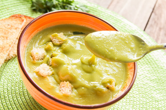 Pea soup in an orange plate with crackers