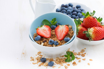 healthy food - granola, fresh berries and jug of milk on table