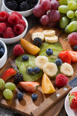 ingredients for fruit salad on wooden board, vertical
