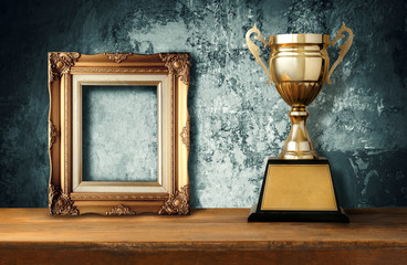 vintage frame with gold trophies on wood table