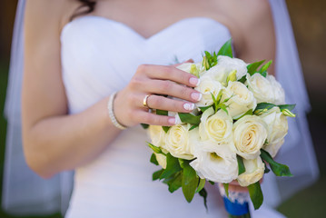 Obraz na płótnie Canvas bride holds fresh white bouquet closeup outdoor