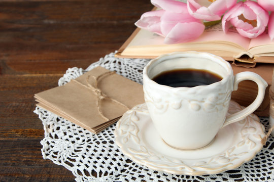 fragrant pink tulips near the books with a Cup of strong coffee and paper on wooden background