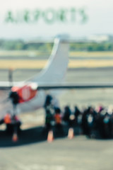 At the airport. Word "Airport" written on the window, group of people coming in the airplane in the background, out of focus