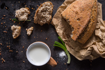 Black food background with homemade bread loaf and  fresh aromatic ruccola , copy space. Top view