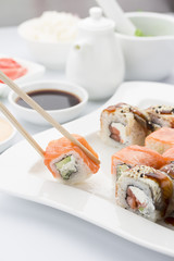 Salmon sushi roll in chopsticks
