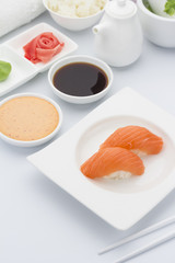 Salmon sushi nigiri with ginger wasabi and soy sauce on a white plate