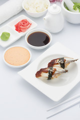 Eel sushi nigiri with ginger wasabi and soy sauce on a white plate