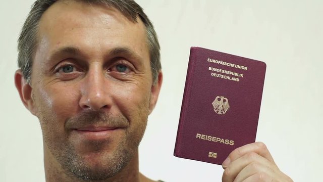 Closeup portrait shot of a happy middle aged male with a German passport ID which is needed to go on vacation or take business trips outside of Germany and the EU to other countries of the world.