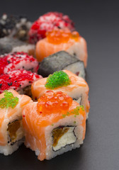 Japanese cuisine. Set of sushi mix roll with differen fresh ingredients over black background ( table ).