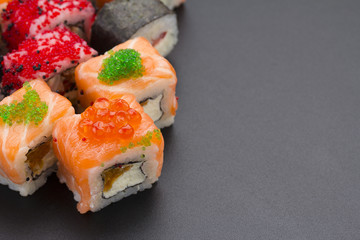 Japanese cuisine. Set of sushi mix roll with differen fresh ingredients over black background ( table ).