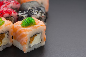 Japanese cuisine. Set of sushi mix roll with differen fresh ingredients over black background ( table ).