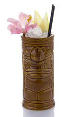 Tropical cocktail served in a tiki style glass and garnished with fruits isolated on white...