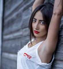 Portrait of a beautiful brunette with brown eyes, black hair  white blouse, vest and denim shorts