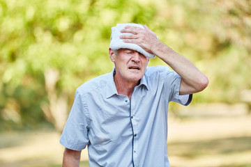 Alter Mann kühlt Kopf mit feuchtem Tuch
