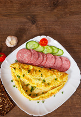 omelet with salami in a plate on wooden table