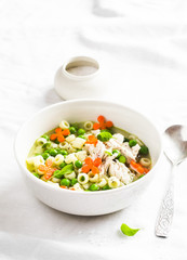 Chicken soup with vegetables and pasta on a light background