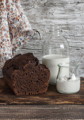 Chocolate cake, milk bottle, yogurt on rustic wooden background
