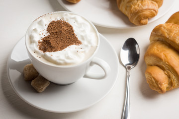 Croissants with cup of coffee on wooden background
