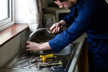 Plumber fixing the sink with wrench