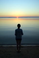 Girl on the shore beach of the Curonian Spit in Nida (Lithuania) and lonely sunset. It is time for yourself
