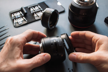 Photo camera lens repair set. Technician engineer disassembling, align and adjusts 50 mm 1.4 photo camera lens. Engineer's hands and maintenance support of broken photographic optic and optical part.