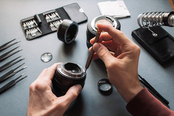 Photo camera lens repair set. Technician engineer check optics alignment and maintenance support of broken photographic 50 1.4 photo camera lens part. Pov to workplace and engineer's hands.