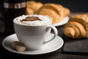 Croissants with cup of coffee on wooden background
