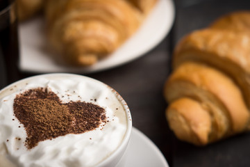 Croissants with cup of coffee on wooden background