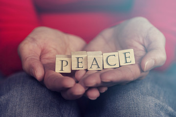 Hands holding Peace message formed with wooden blocks