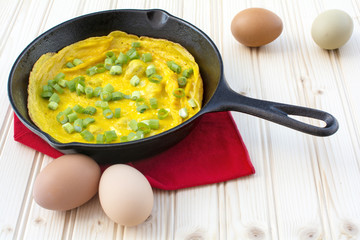 Omelette in cast iron skillet on wood background