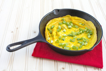 Omelette in cast iron skillet on wood background