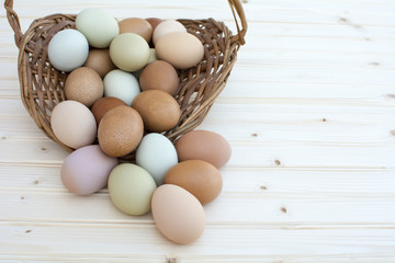 Fresh organic chickeneggs overflow out of basket on wooden backg